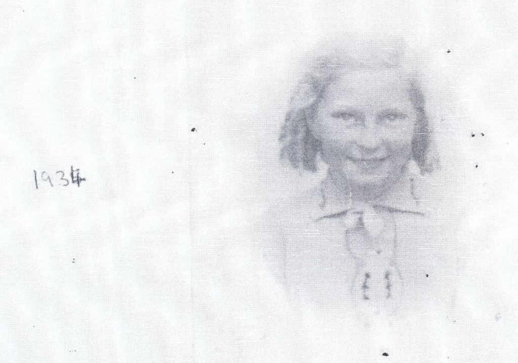 A very faded photocopy of a head-and-shoulders portrait of a young girl with shoulder-length hair and a collared blouse, with “1934” handwritten to the left.