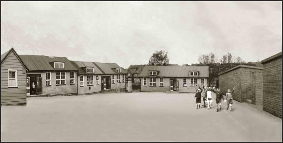Sepia photograph of a wide school playground surrounded by single-storey timber classroom huts with dormer windows; a group of small children with boxes on straps wave near the brick air-raid shelters on the right.
