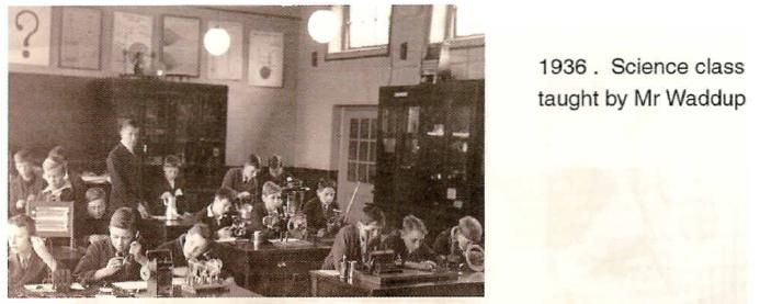 A scanned booklet page: boys at benches with scientific apparatus in a laboratory with glass-fronted cabinets and hanging lamps, a teacher standing among them. Printed beside it: “1936. Science class taught by Mr Waddup”.
