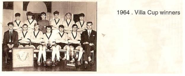 A scanned booklet page: a boys’ football team in V-necked shirts with two men in suits, a shield and a trophy on the floor in front. Printed beside it: “1964. Villa Cup winners”.