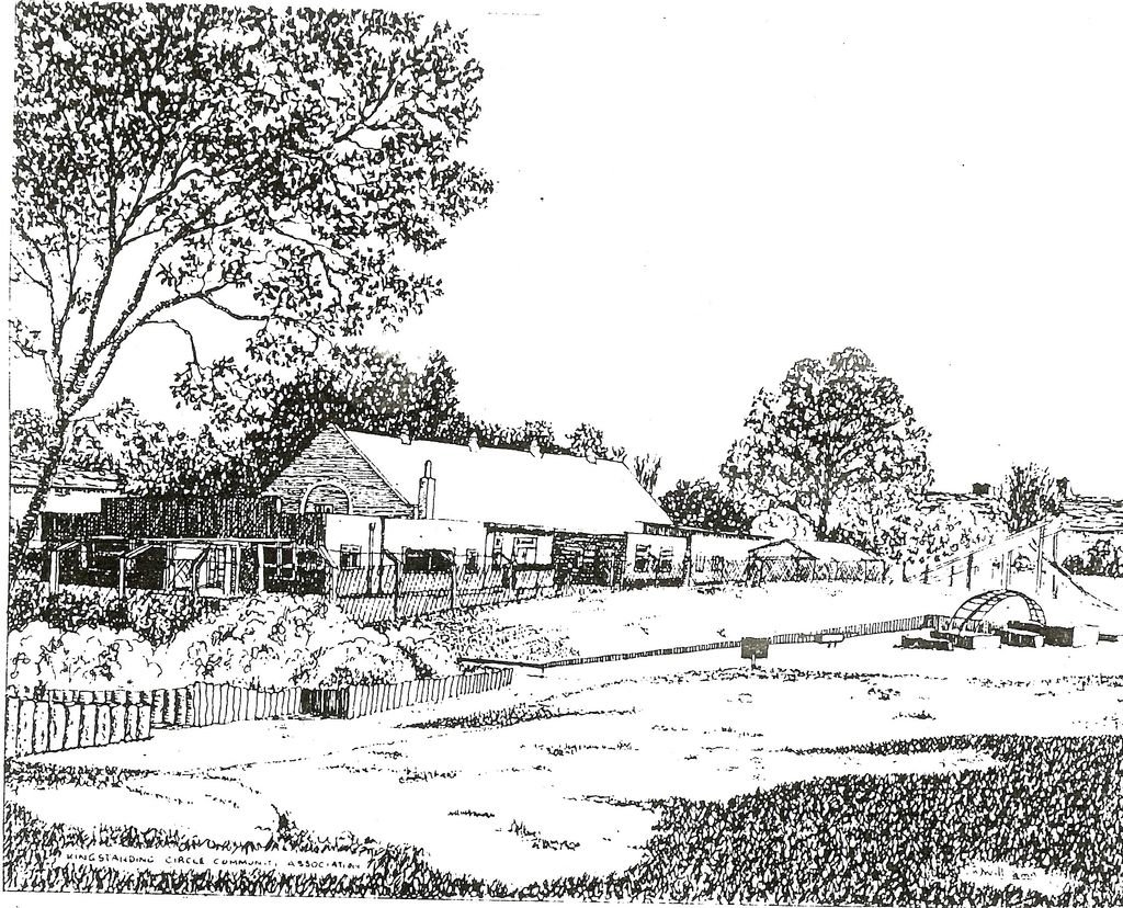 A black-and-white pen drawing of a long, low community building with flat-roofed extensions in front of an older gabled hall, behind a picket fence and a large tree, with an open grassy space and a small climbing arch in front. Lettering along the bottom reads “Kingstanding Circle Community Association”.
