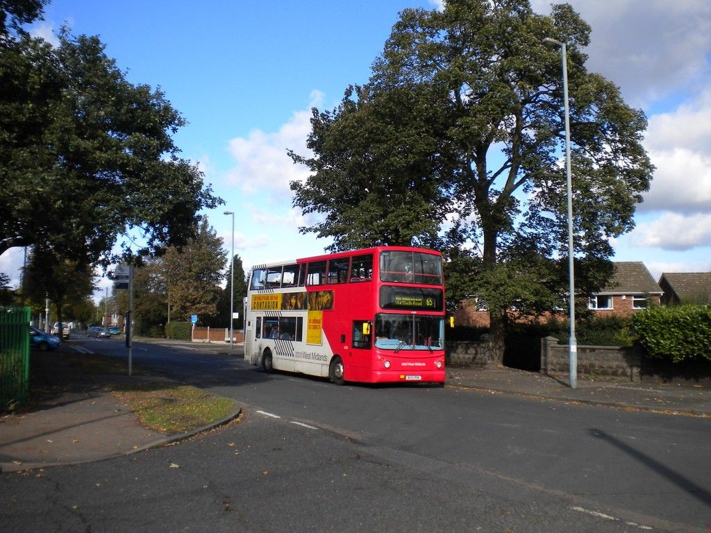 Red and white double-decker bus turning through Court Lane under big trees at the Perry Common bus terminus