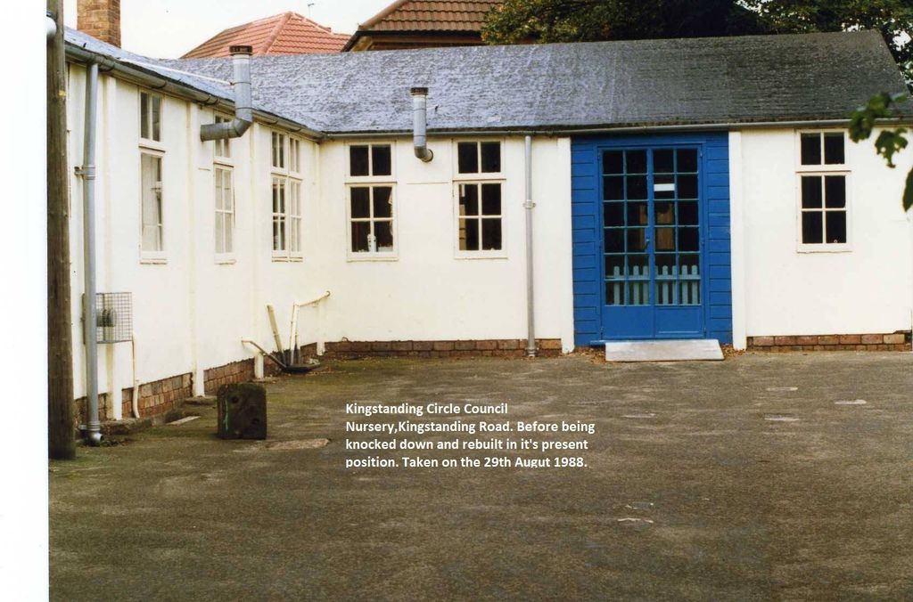 A white single-storey prefabricated building with a blue-framed glazed door and metal flues, on a tarmac yard