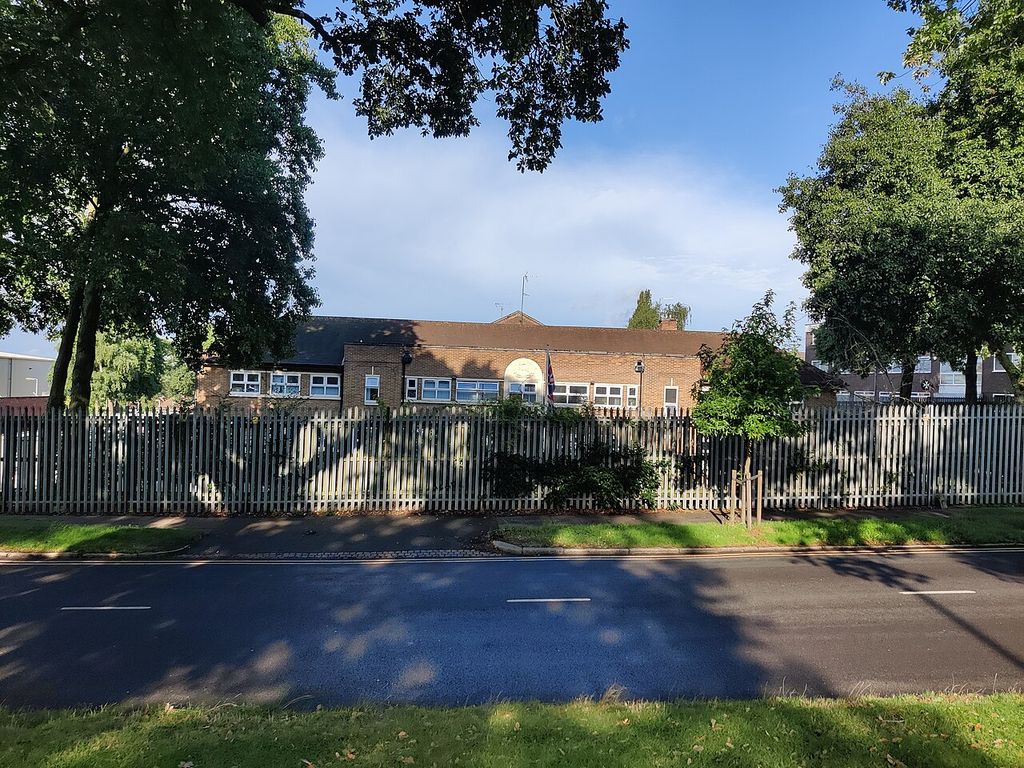 The Army Reserve Centre on Kingstanding Road: a long two-storey brick building with a white crest panel, behind green palisade fencing and trees.