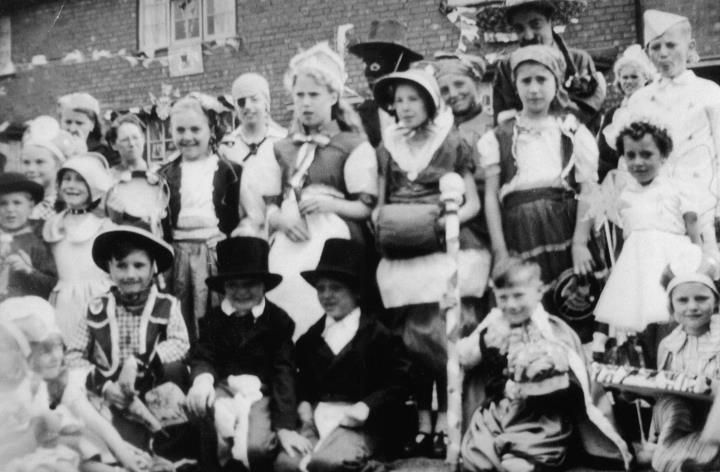 Children in fancy dress, some in top hats and bonnets, crowded together for a photograph.