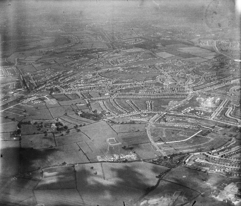Oblique aerial photograph from the north-west: fields in the foreground and the new estate spreading across the middle distance.