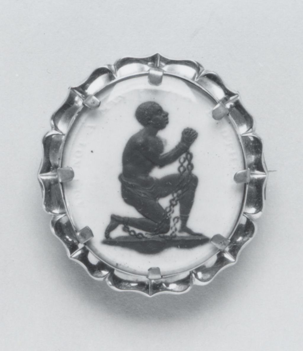 Oval white ceramic medallion showing a kneeling black figure in chains, with the words Am I Not a Man and a Brother.