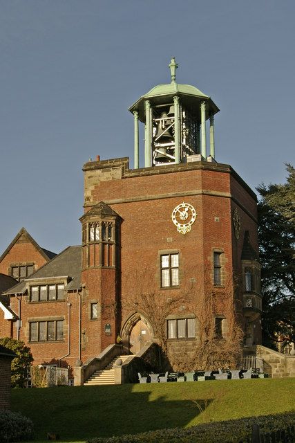 Brick school tower topped by an open copper-roofed cupola holding bells.