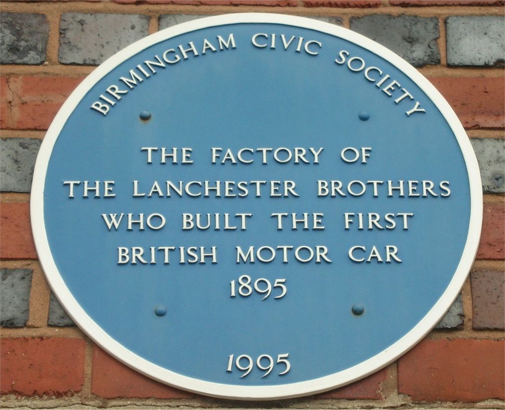 Oval blue Birmingham Civic Society plaque on banded red and blue brickwork, reading The factory of the Lanchester brothers who built the first British motor car 1895, dated 1995.
