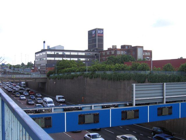 Brick factory with a large HP sign on its roof, with demolition machinery in front.