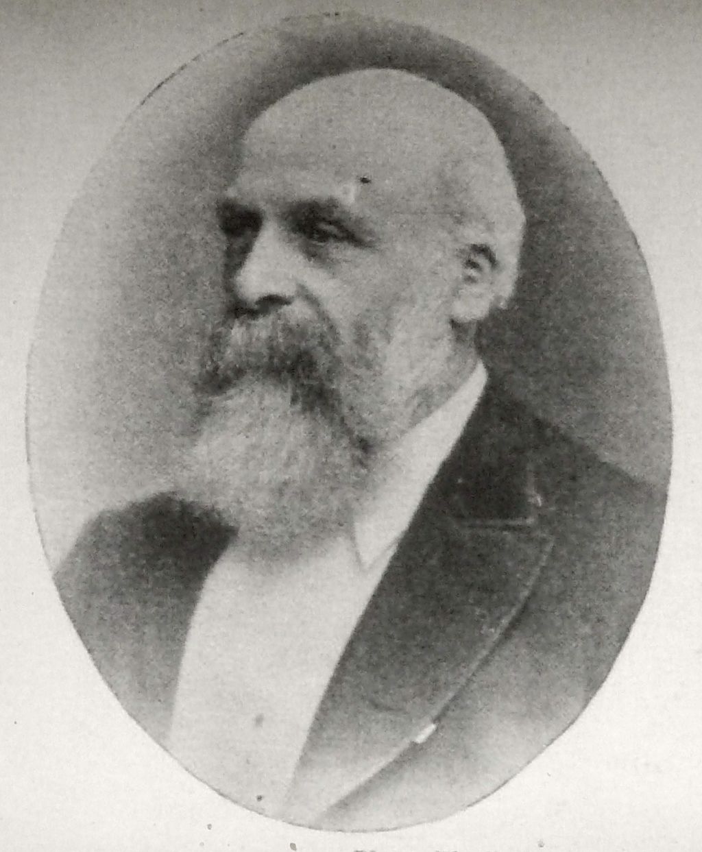 Oval photographic portrait of a balding Victorian man with a long white beard, in a dark coat, looking to the left.