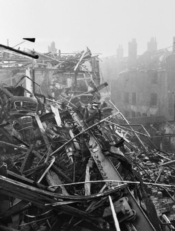 A pile of girders, timber and rubble at a street corner.