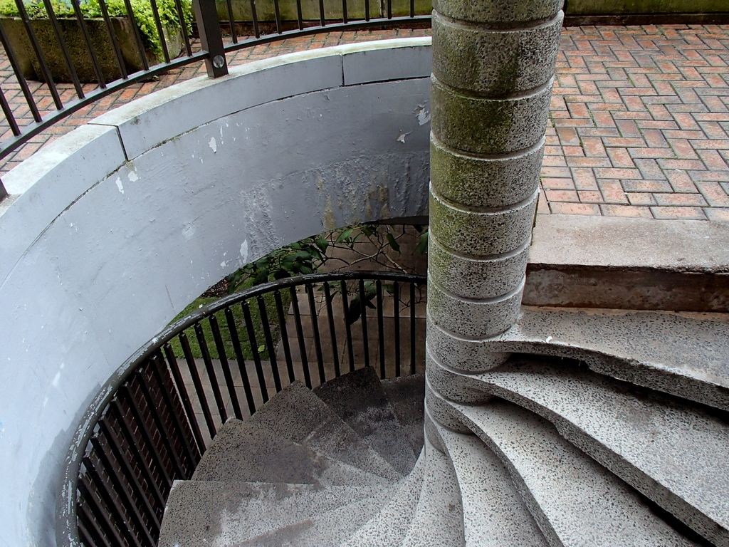 A concrete spiral staircase leading down to a road level.