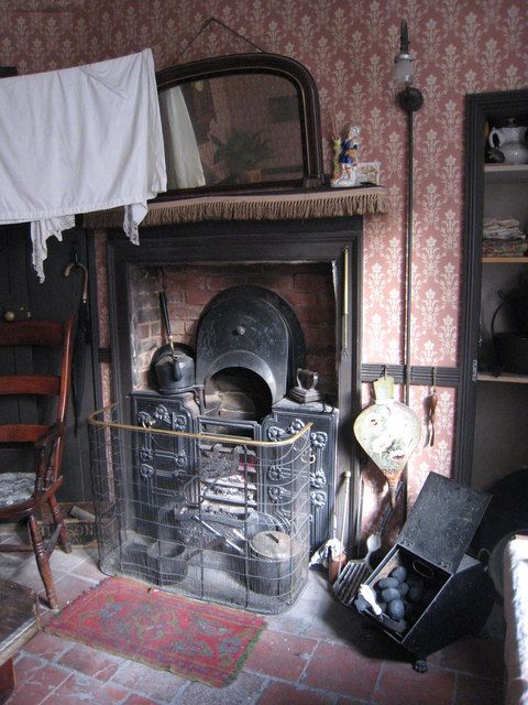 A small room in a restored back-to-back house, with a black cast-iron range, a mantelpiece and washing hung to dry.