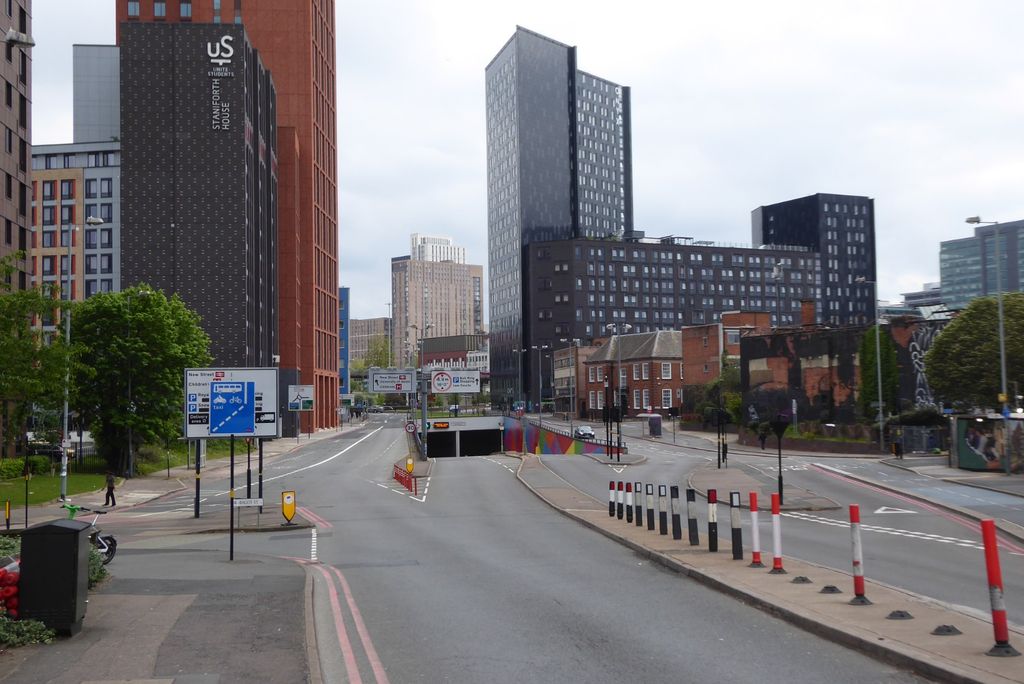 A wide city road dipping towards an underpass, with tall modern blocks beyond.