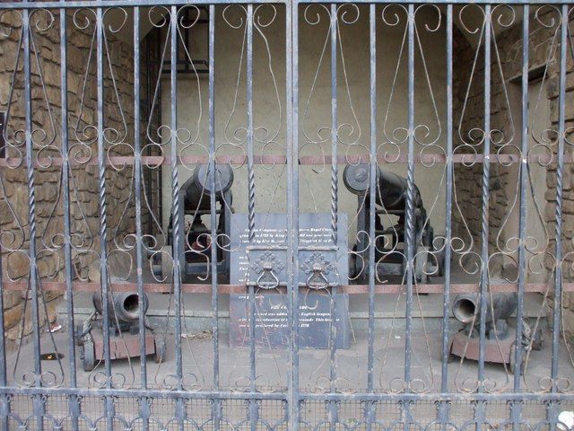Short iron cannon on carriages displayed in the arched base of a stone tower.
