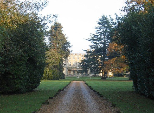 A large plain eighteenth-century country house in parkland.