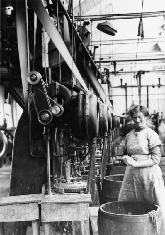 A woman at a workbench making small brass cartridges.