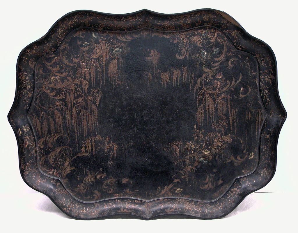 A black papier-mâché tray with a shaped edge, painted with gold scrolls, weeping willows and small flowers.