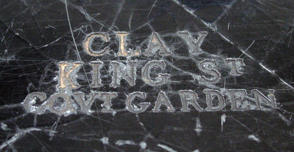 Close-up of a black lacquered surface stamped in capitals ‘CLAY KING ST COVT GARDEN’.