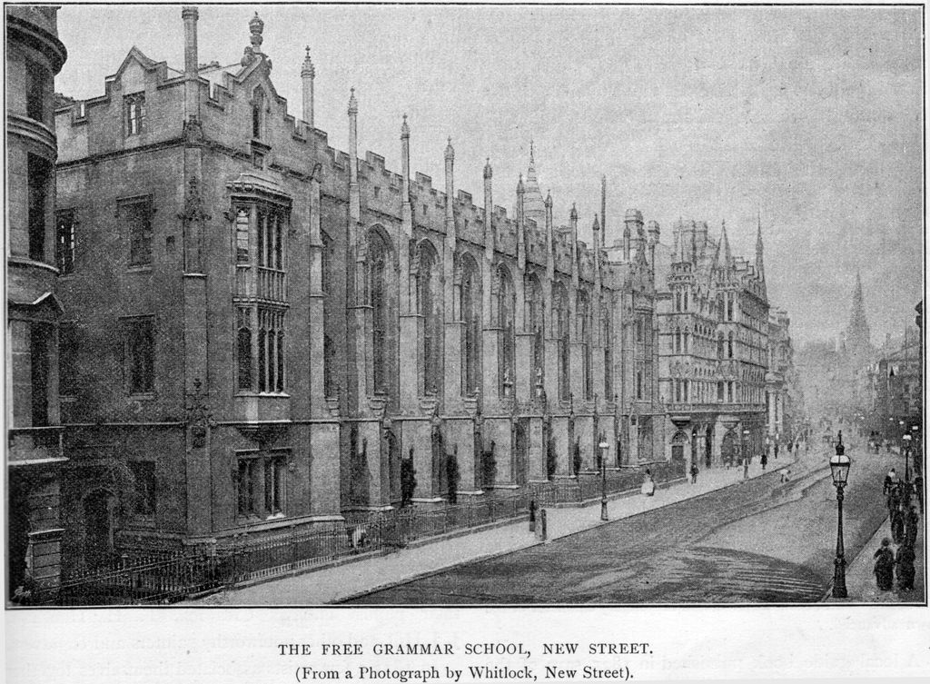 Engraving of a long Gothic stone school front on a city street, with tall pinnacled buttresses, a corner oriel window and iron railings.