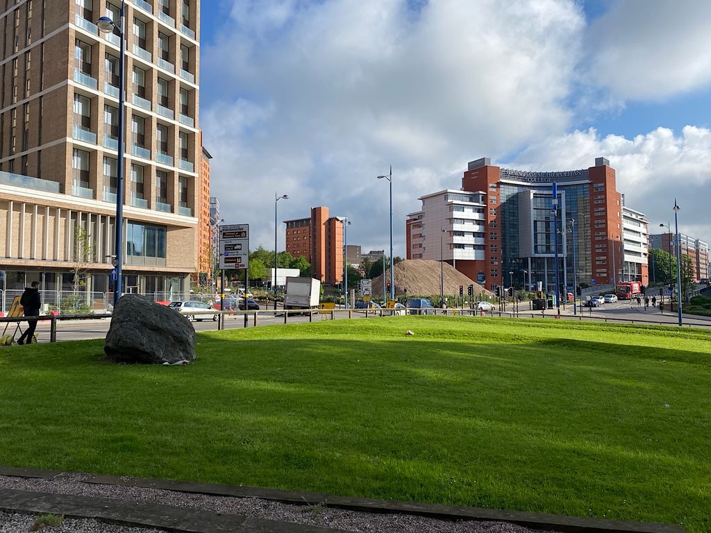 An open lawn among modern apartment buildings.