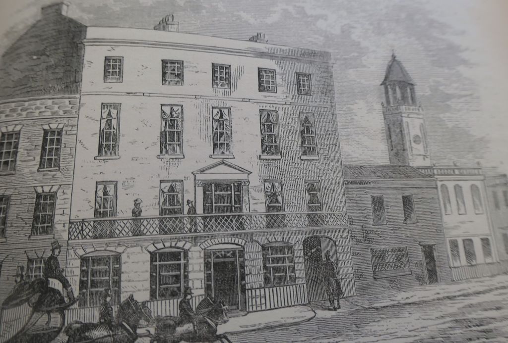 Victorian engraving of a hotel’s balconied front on a city street.