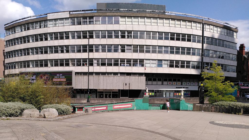 A 1960s office building with a curved corner at a large roundabout.
