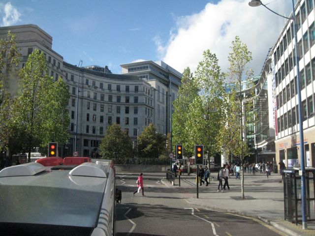 A busy road junction with office blocks, seen from a bus.