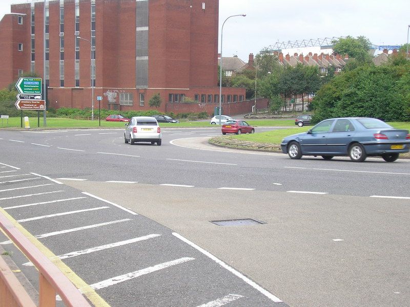 A roundabout and dual carriageway climbing away under a grey sky.