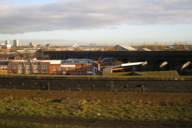 A disused brick viaduct crossing industrial premises.