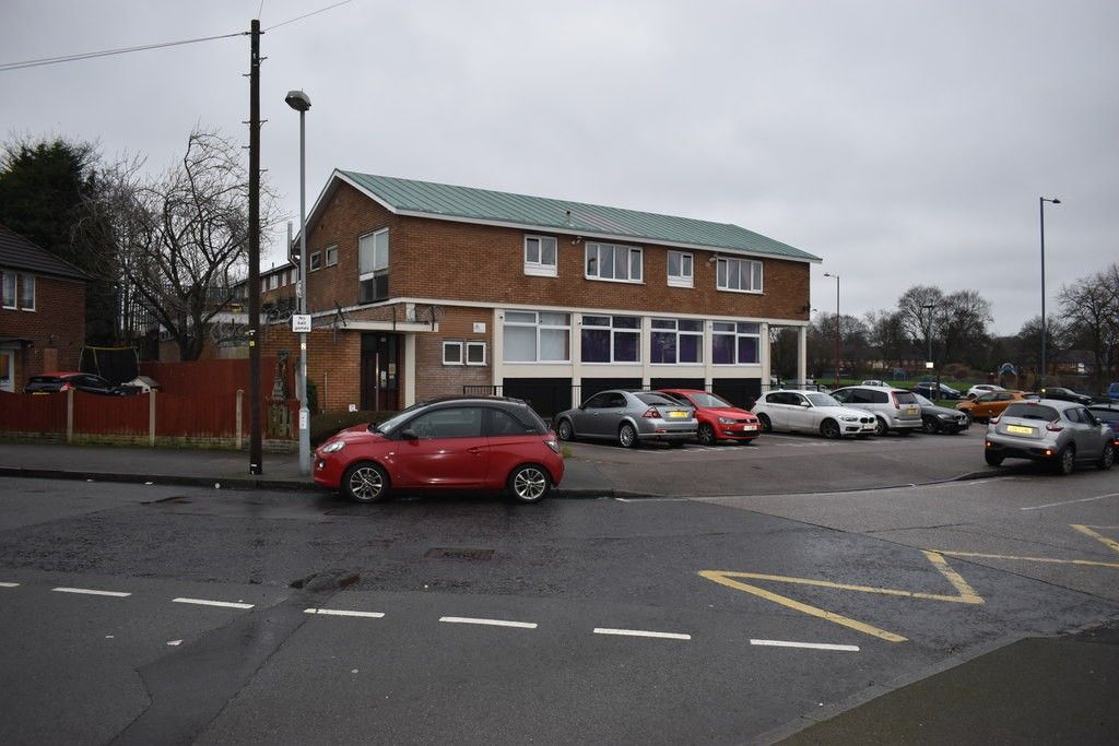 Two-storey brick library building with a band of windows on the ground floor, facing a car park near the Circle