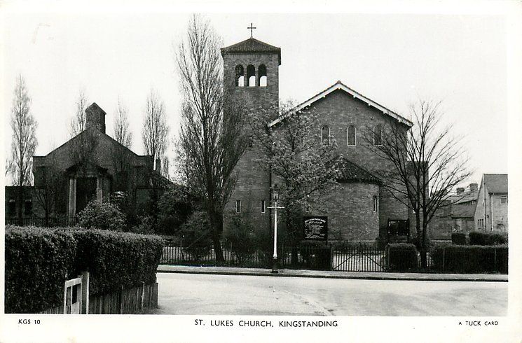 Black-and-white postcard of St Luke’s Church, Kingstanding, around 1950: a brick church with a tall bell tower behind hedges and railings